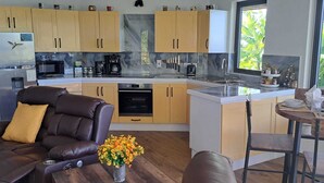 Eine moderne Küche mit Kochinsel, Holzschränken und einer Essecke mit Tisch und Stühlen.