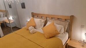 Ein ordentlich bezogenes Bett mit einem Holz-Kopfteil, einer gelben Bettdecke und zwei Kissen.