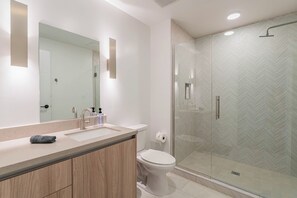 A modern bathroom with a glass shower enclosure, a sink with a mirror, and a toilet. - Saiya  1118 (Phoenix)