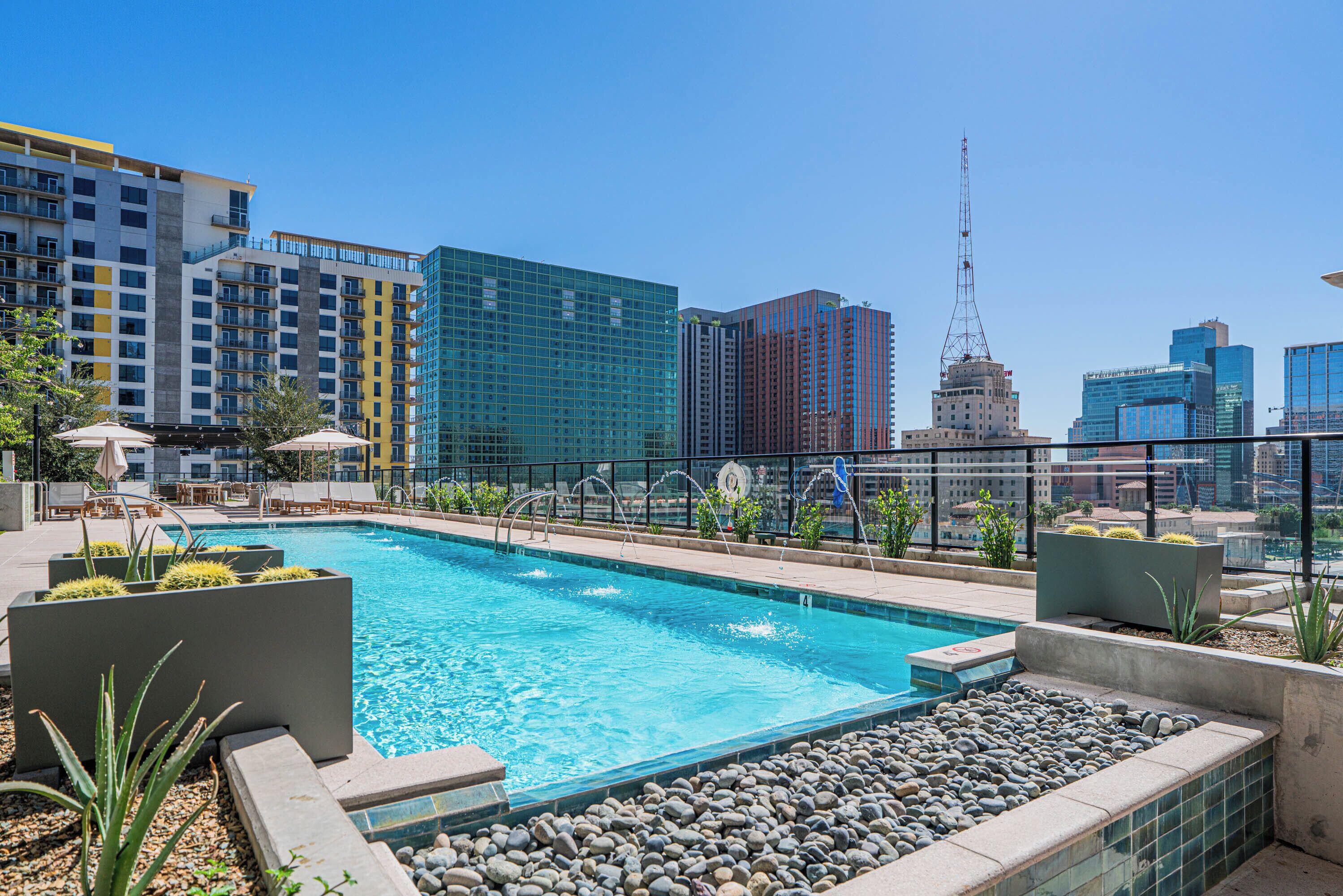 A rooftop pool with a cityscape view, surrounded by modern buildings and a clear sky.