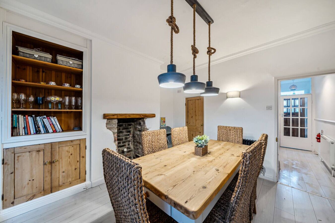 A dining area with a large table, pendant lights, and a feature fireplace.