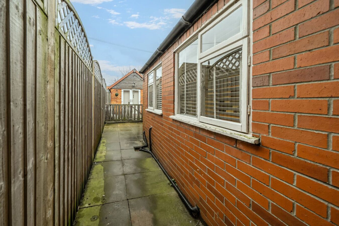 Step outside into a paved passageway beside the property.