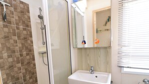 A bathroom with a shower, a sink, and a mirror. - Beachcombers (Wareham)