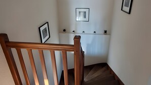 A staircase with wooden railings and a landing area with a shelf. - Gîte du lavoir: Village House in the Countryside (Champs sur Tarentaine Marchal)