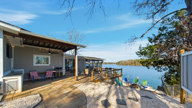 Une terrasse au bord du lac, avec des sièges d’extérieur, une pergola et une vue sur le lac.