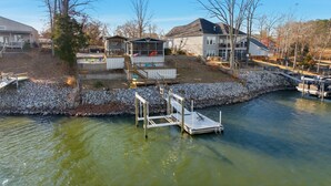 Une propriété située au bord de l’eau, dotée d’un quai, d’un petit bateau et d’une maison avec une véranda.