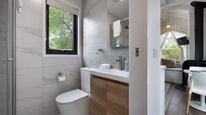 A modern bathroom with a toilet, sink, and shower. - Piccola Verde Tiny House (Hepburn)