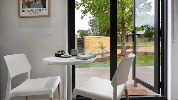 Une pièce moderne avec deux chaises blanches, une petite table ronde et un tableau encadré accroché au mur.