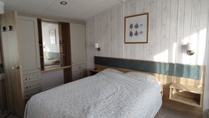 A bedroom with a bed, a wardrobe, a mirror, and a framed picture on the wall. - Rockley Park - Harbour View, No 67 (Poole)