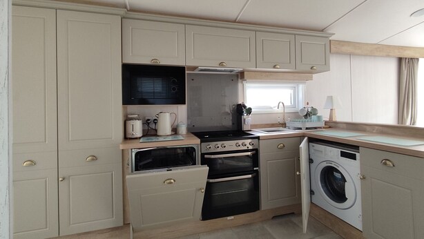 A compact kitchen with built-in appliances, a window, and a sink. - Rockley Park - Harbour View, No 67 (Poole)