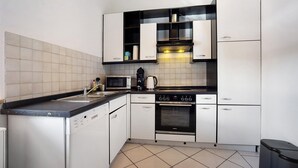 A modern kitchen with white cabinets, a black countertop, a built-in oven, and a microwave. - Apartment 'Schnitzer' with Balcony and Wi-Fi (Görisried)