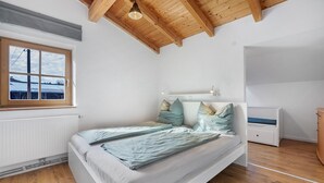 A bedroom with a wooden ceiling, a window, a bed, a bedside table, and a radiator. - Apartment 'Schnitzer' with Balcony and Wi-Fi (Görisried)