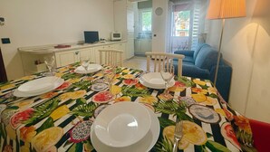 En matplats med ett bord dukat för fyra personer, en blå soffa och en lampa.