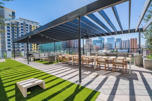 An outdoor patio with a grill, seating, and a view of the city skyline. - Saiya  1120 (Phoenix)