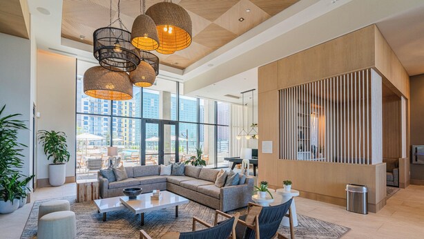 A spacious living area with a sectional sofa, a coffee table, and a seating area with chairs. There are large windows providing a view of the cityscape. - Saiya  1120 (Phoenix)