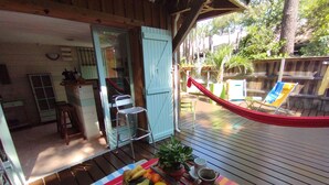A wooden deck with a table set with fruits and a vase, a hammock, and a slide in the background.