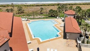 A swimming pool with lounge chairs, a beach view, and a building with a red roof. - 
Amazing waterfront condo with an amazing view of the beach, an amazing sunrise (Palm Coast)