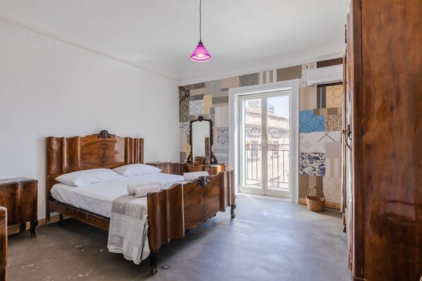 Ein Schlafzimmer mit einem hölzernen Bett, einer Pendelleuchte und Blick durch eine Glastür.