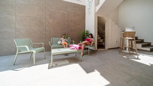 A spacious indoor area with two green chairs and a bench, a staircase, and a desk with a chair.