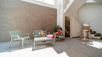 Un espace intérieur spacieux comprenant deux fauteuils verts et un banc, un escalier et un bureau avec une chaise.