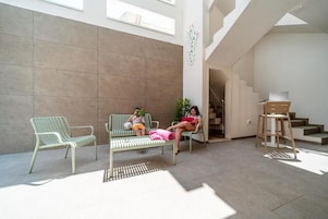 Un espace intérieur spacieux comprenant deux fauteuils verts et un banc, un escalier et un bureau avec une chaise.