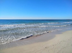 Une plage avec une eau d’un bleu limpide et un rivage sablonneux.