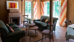 A cozy living room with a fireplace, green sofas, and a dining table. - Alcor Exclusive Friedrichsruh (Aumuehle)