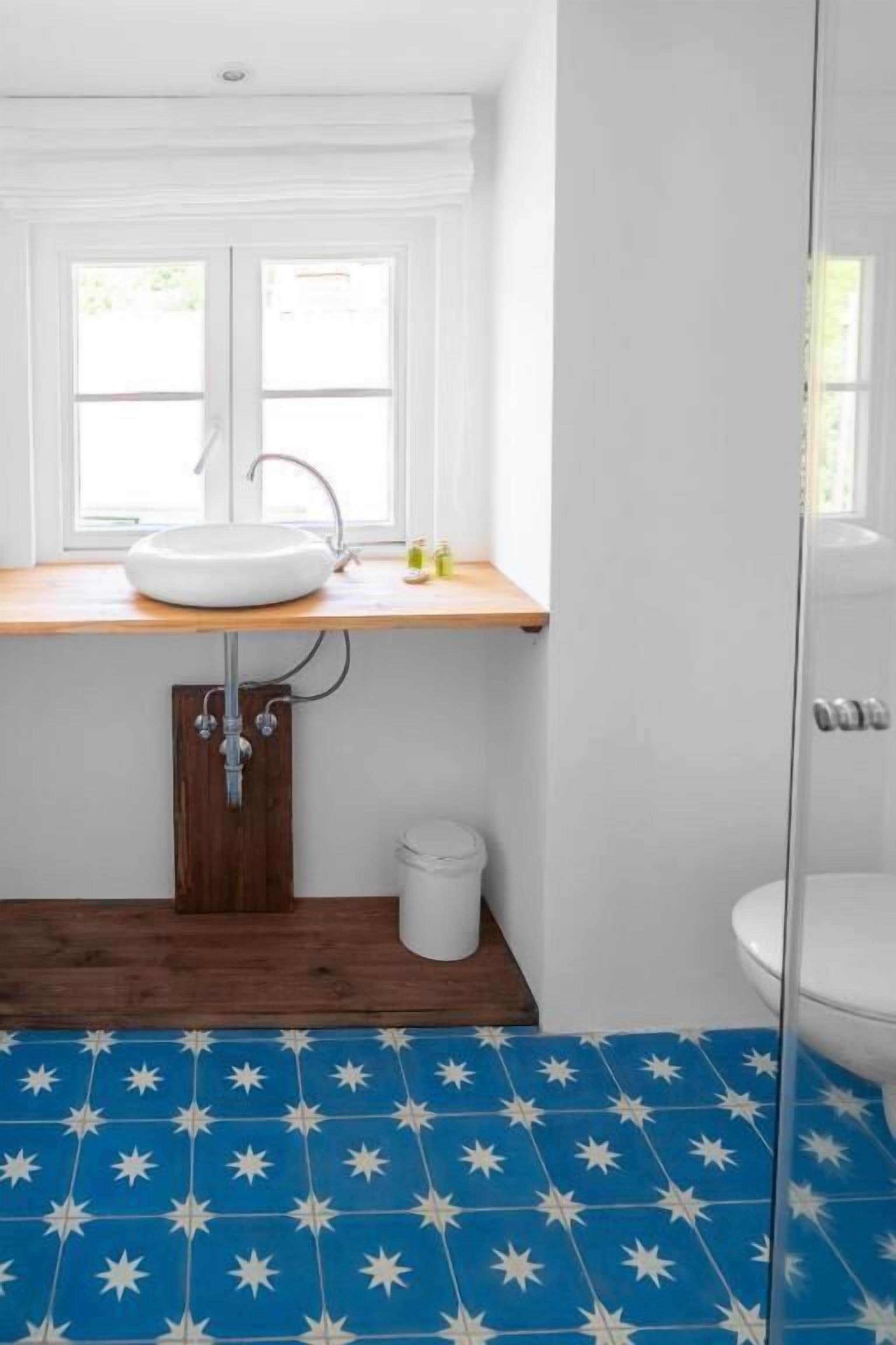 A bathroom with a white sink, wooden countertop, and a blue star-patterned floor.