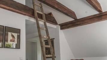 A bedroom with a wooden ladder, a chair, and a bed.