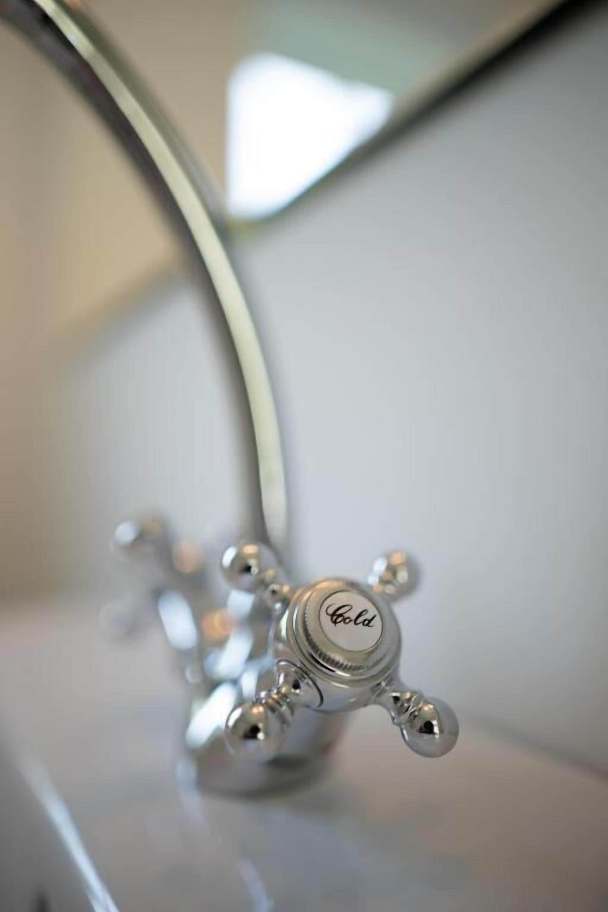 Ein Detailaufnahme eines silbernen Wasserhahns, auf dem das Wort 'Gold' eingraviert ist.