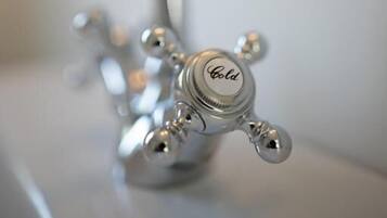 Ein Detailaufnahme eines silbernen Wasserhahns, auf dem das Wort 'Gold' eingraviert ist.