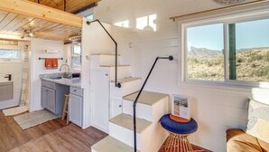 A compact kitchen with a sink, a wooden ceiling, and a window overlooking a desert landscape. - Incredible Views at Tiny Heaven In Cottonwood (Cottonwood)