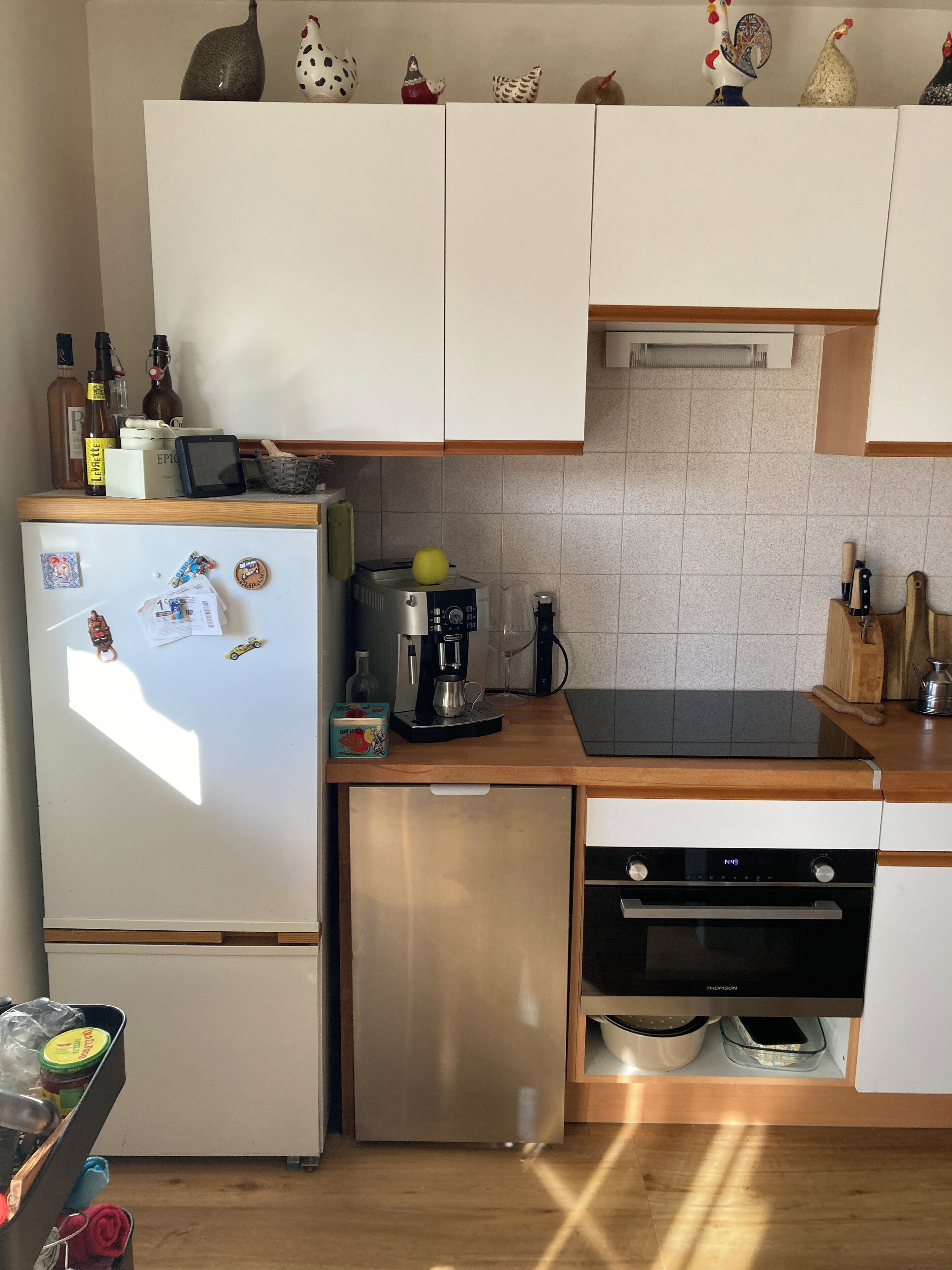 A compact kitchen with white cabinets, a built-in dishwasher, and a coffee maker.