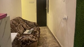 Ein schmaler Flur mit Schlafsofa, Wandfernseher und einer Tür am Ende.