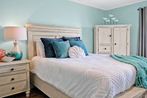 A bedroom with a bed, nightstands, a dresser, and a lamp. - Ocean View Condo Walk to Tiki Bar & Beach (Carolina Beach)