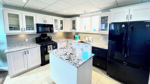 A modern kitchen with white cabinets, a black refrigerator, a microwave, and a stove. - Close to beach SAUNA & Movie Room/Sherkston (Port Colborne)