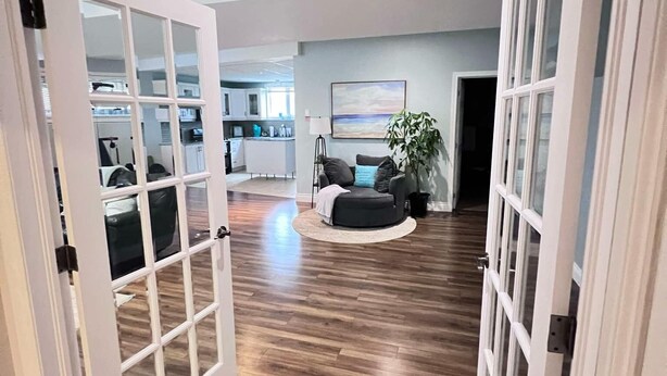 A spacious living area with a wooden floor, a round seating area, and a kitchen in the background. - Close to beach SAUNA & Movie Room/Sherkston (Port Colborne)