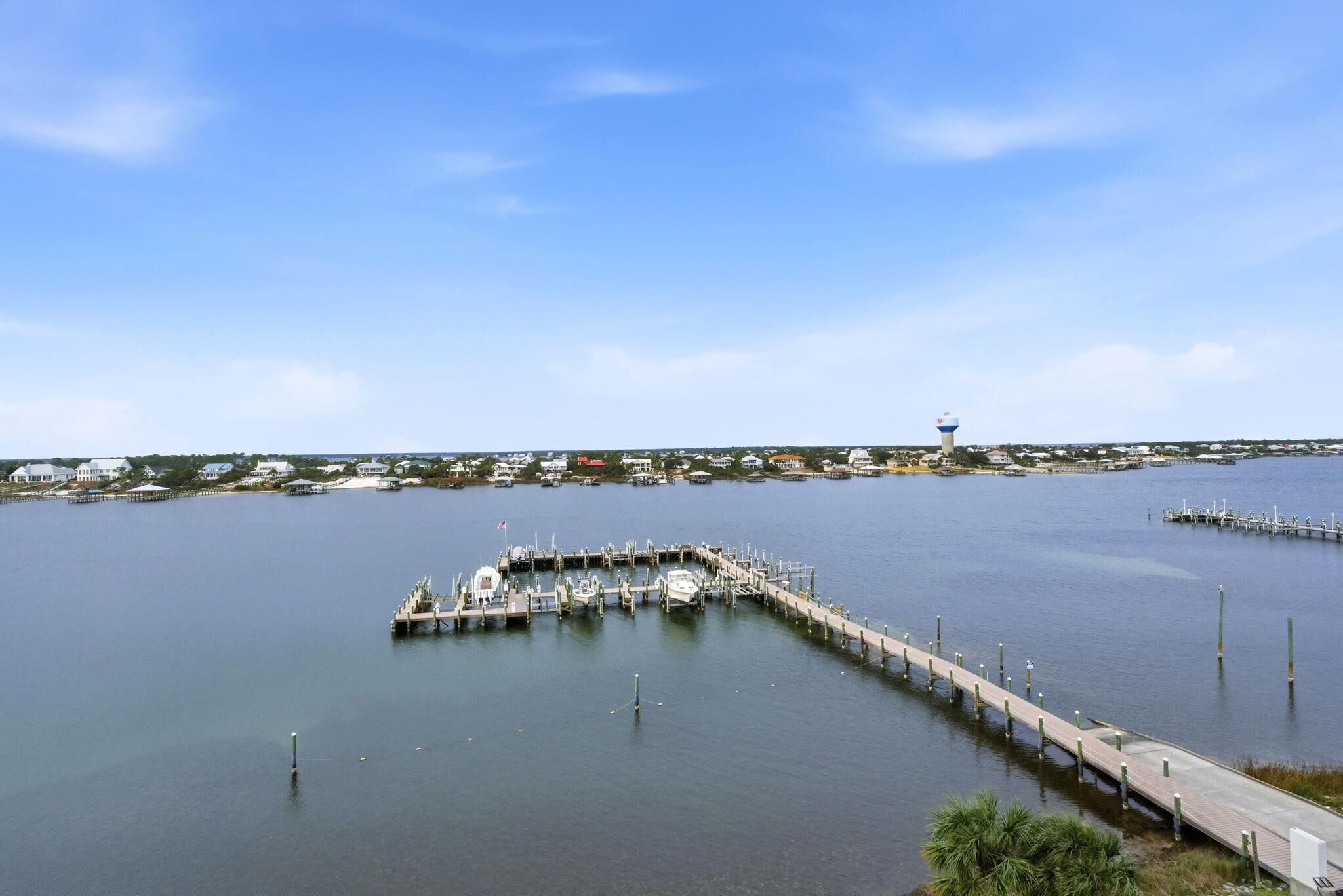 A marina with docks extending into calm water, surrounded by residential buildings and a clear sky.
