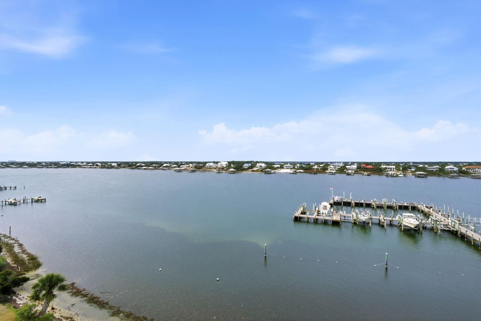 A marina with docks and boats, surrounded by calm water and a clear sky.