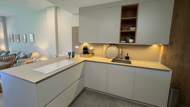 Una cocina moderna con armarios blancos, una isla integrada y una pared decorativa de madera.