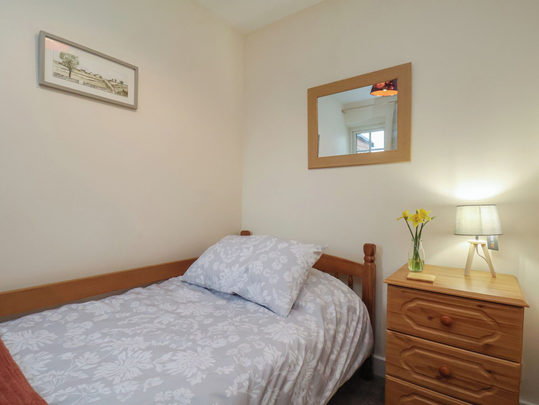 A bedroom with a bed, a dresser, a mirror, and a framed picture on the wall.