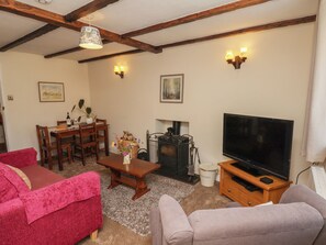 Ein gemütliches Wohnzimmer mit Kamin, Fernseher und bequemen Sitzgelegenheiten.