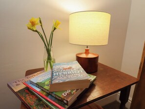 Ein Holztisch mit einer Lampe, einer Blumenvase und einem Stapel Bücher.
