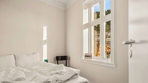 Een slaapkamer met een bed, een raam en een stoel.