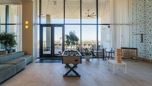 Un vestíbulo amplio con mesa de fútbol, zona de estar y ventanas grandes que ofrecen vistas.