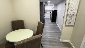 Een moderne keuken met witte kasten, een zwarte koelkast, en een eethoek met een ronde tafel en twee stoelen.