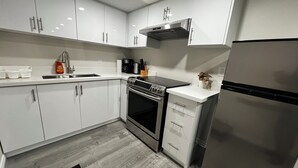 Een moderne keuken met witte kasten, roestvrijstalen apparatuur en een houten vloer.