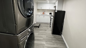 Een compacte keuken met inbouwapparatuur, waaronder een wasmachine, droger en een koelkast.
