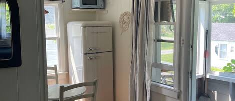 A compact kitchen with a refrigerator, microwave, and a dining area with a table and chairs.