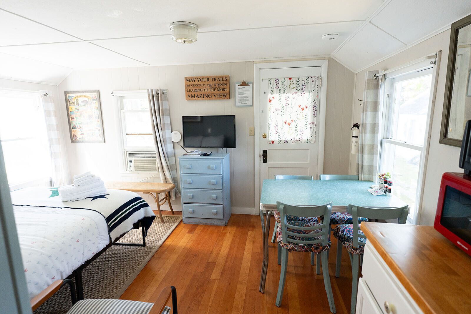 A compact room with a bed, a desk, a chair, a dresser, and a television.
